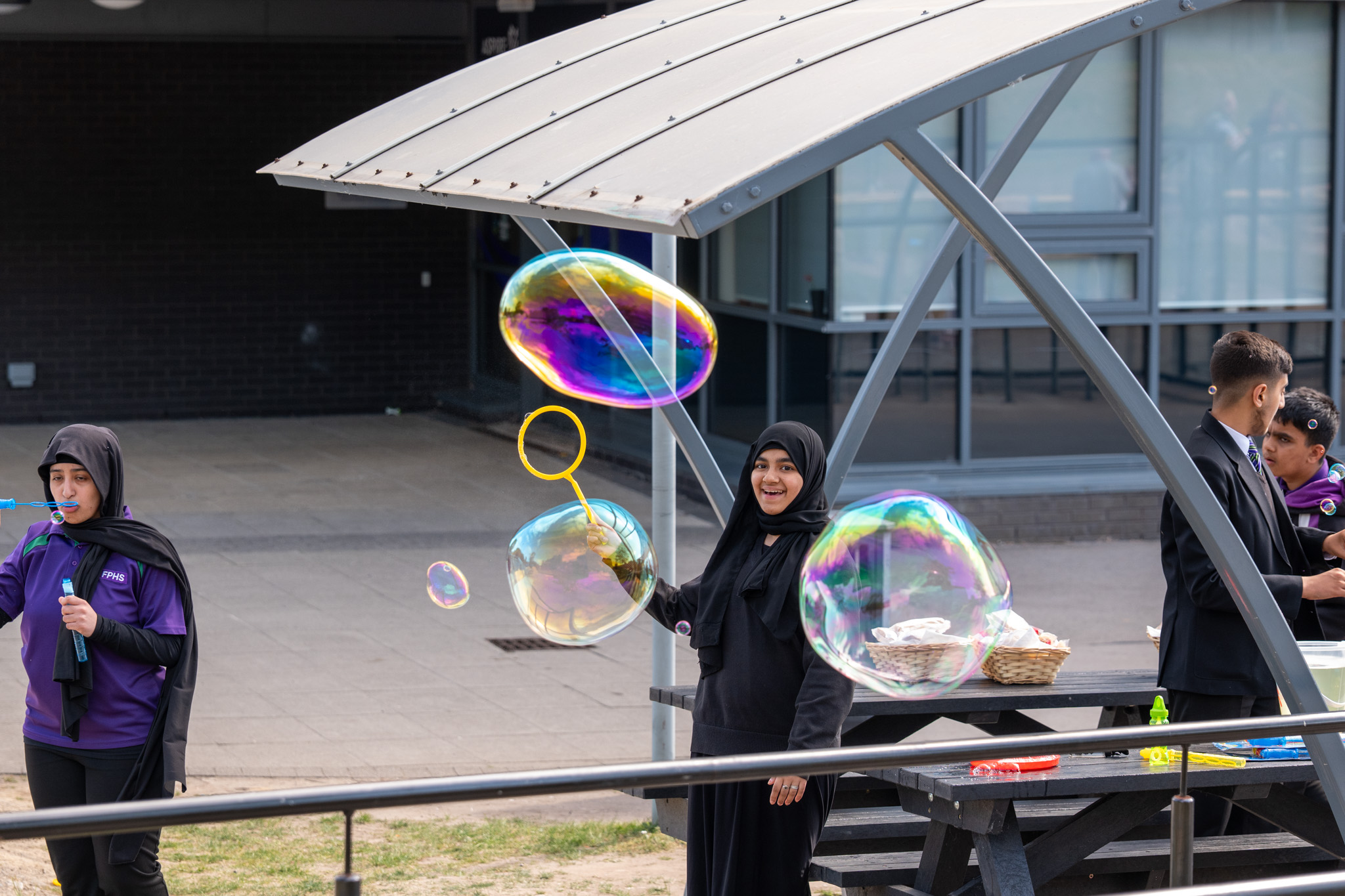 A young high school girl blowing bubbles with a huge smile on her face.